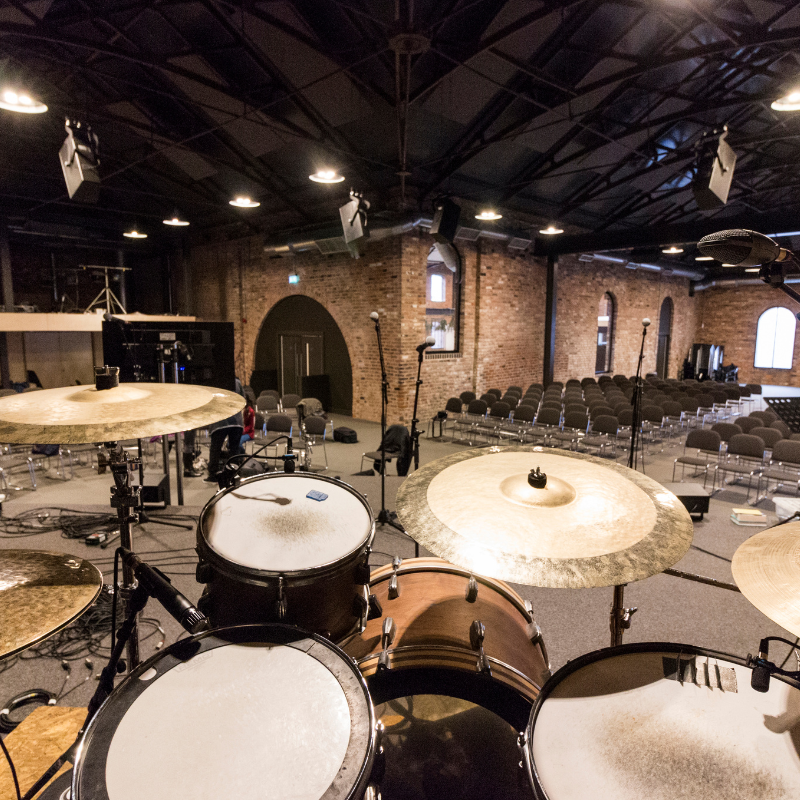Drum set in a large indoor space with brick walls and high ceilings.

