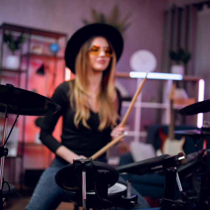 Person playing electronic drums in a room with musical equipment.